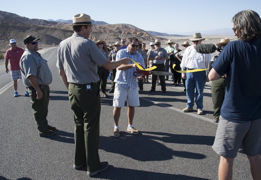 Death Valley National Park Superintendent Mike Reynolds holds a yellow ribbon across Badwater Road while Inyo County Supervisor Matt Kingsley ceremonially cuts it.