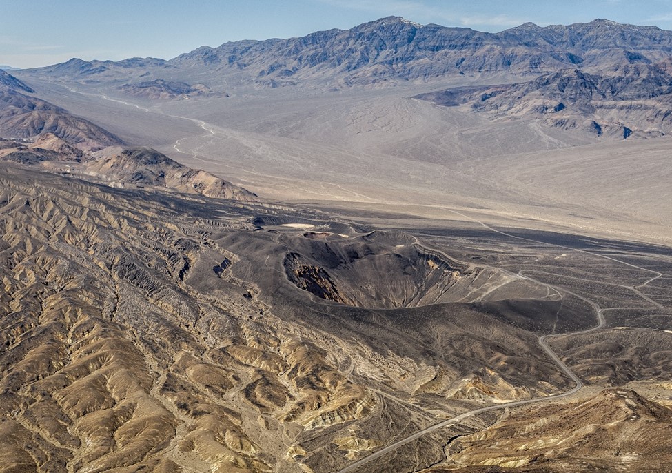 Photo taken from an airplane of brown eroded landscape and black volcanic landscape with craters.