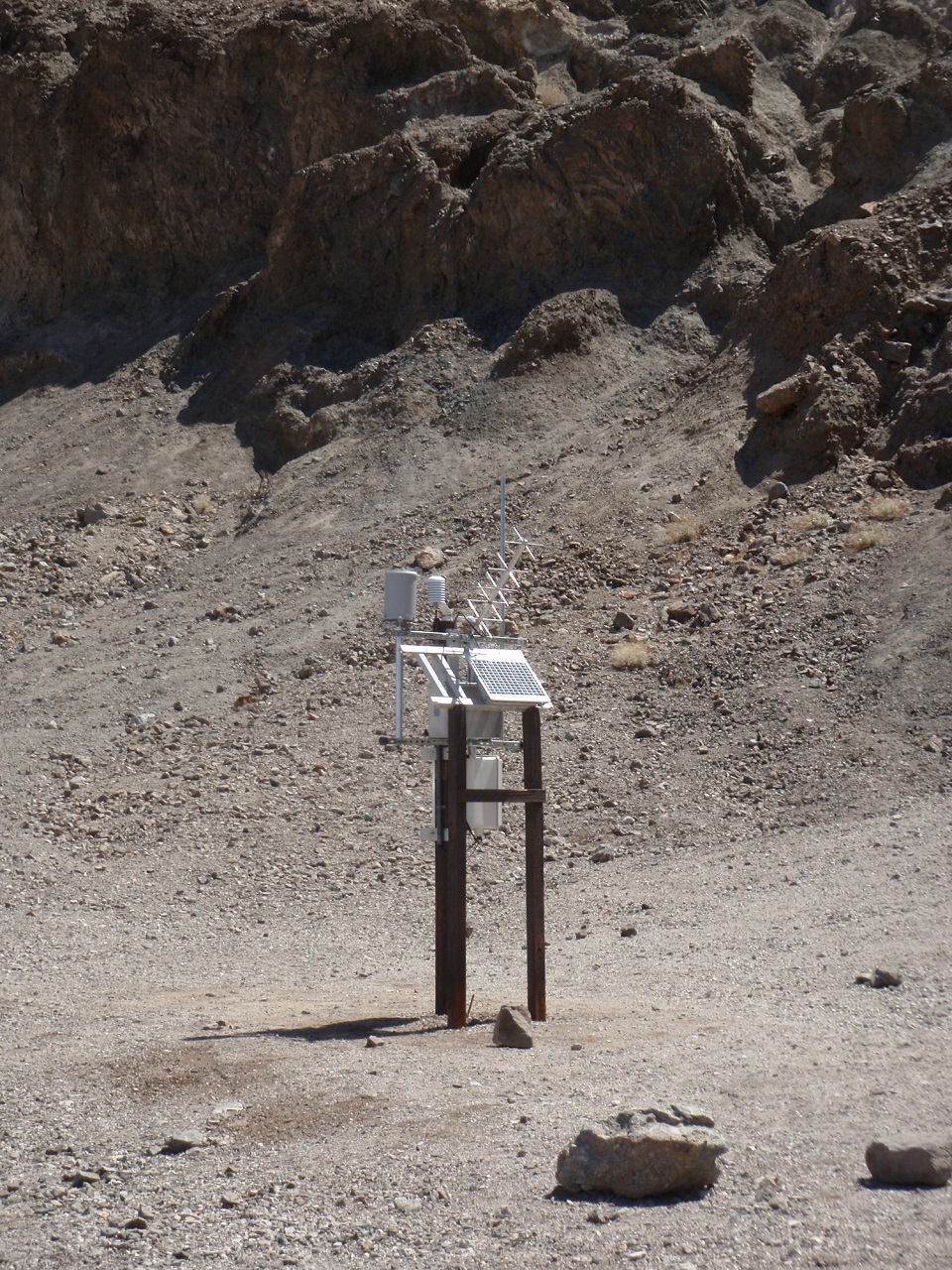 White and gray equipment is on top of wooden posts in a landscape of bare rock.