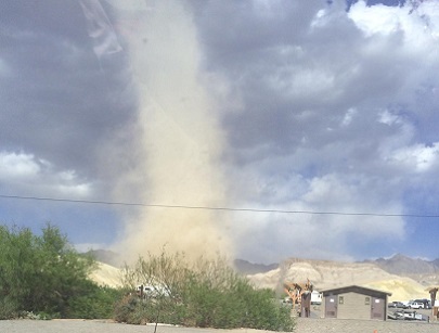 The dust devil is visible to the left that just flipped a pop-up camp trailer (visible to right of restroom).