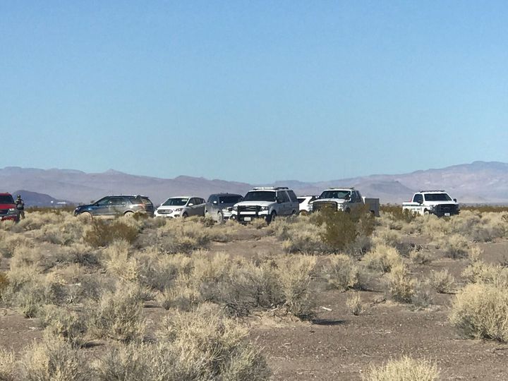 Vehicles from multiple responding agencies are lined up with shrubs in foreground and mountains in the background.