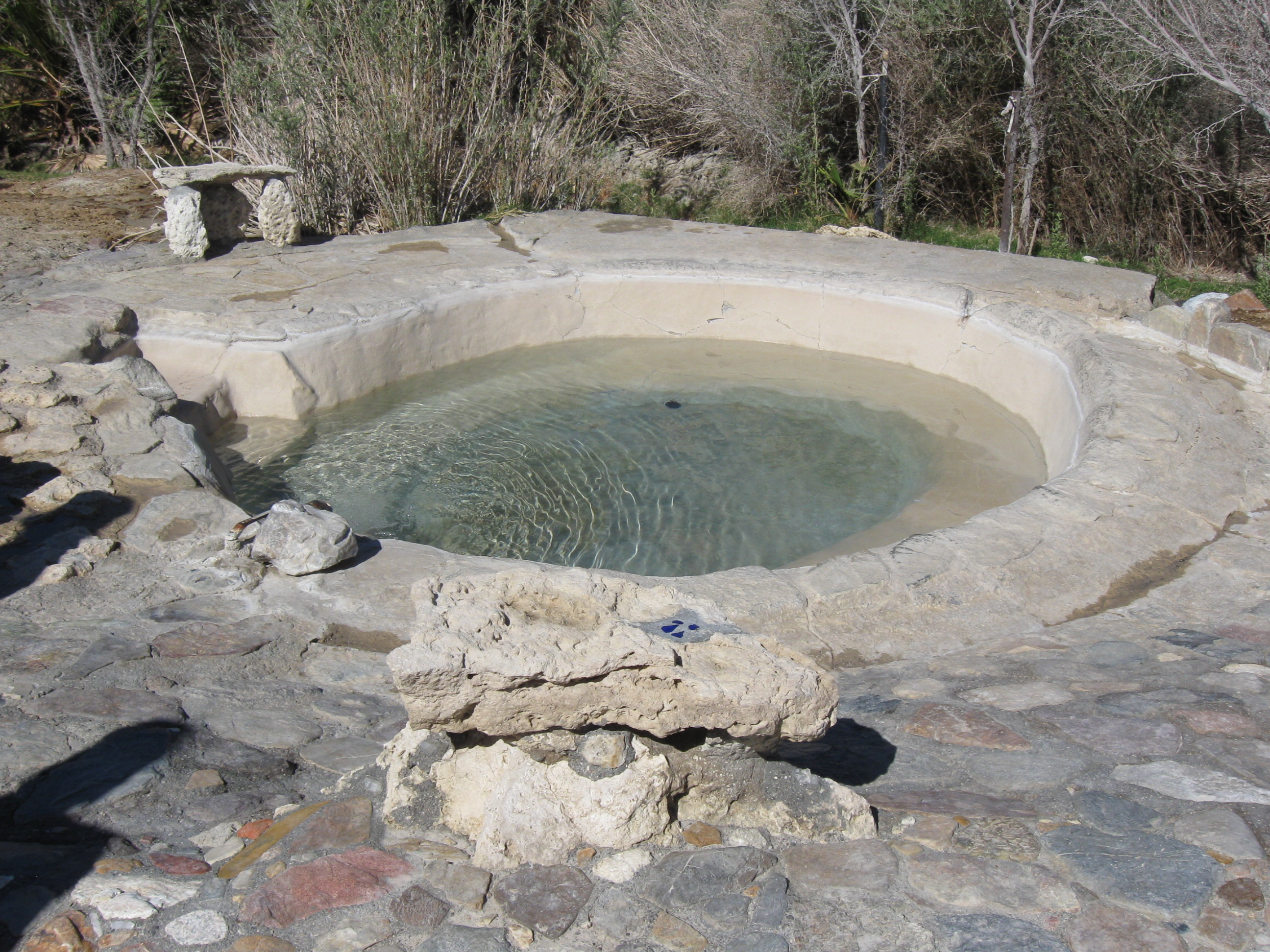 The Sunrise Pool at Saline Valley's Lower Spring is seen as light-colored paving stones surrounding a round stone-lined tub about 10 feet across.