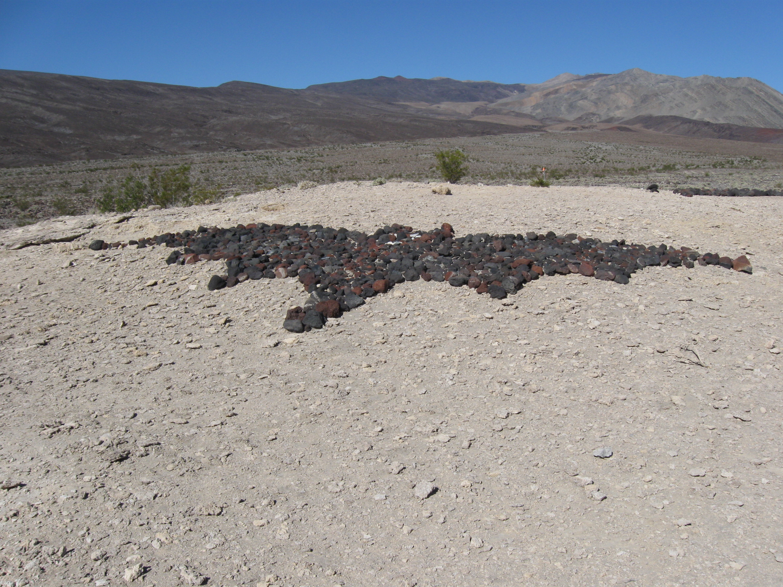 Dark rocks have been placed in the shape of a flying bat on the ground near Saline Valley Warm Springs.