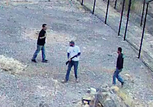 Security camera photo of 3 men and a firearm inside the fenced enclosure at Devils Hole Grainy still image from security camera shows three men inside the fence at Devils Hole.