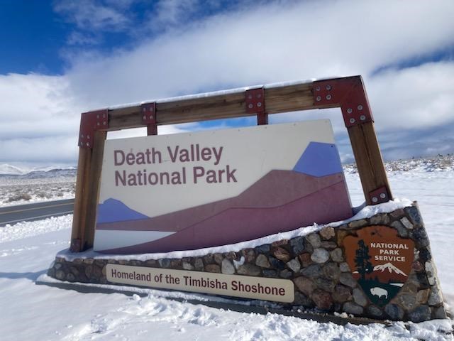 Snow on the ground and on top of a large colorful sign, which says, "Death Valley National Park, Homeland of the Timbisha Shoshone."