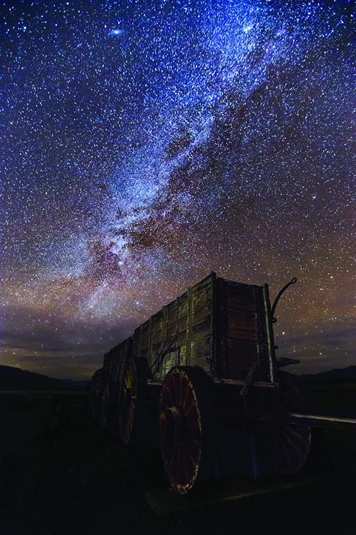 The Milky Way lights up the night sky behind a wagon.