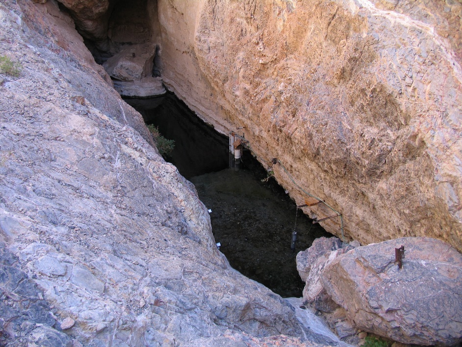 Devil's Hole Close-up Four rocky walls lead down to a pool of water.