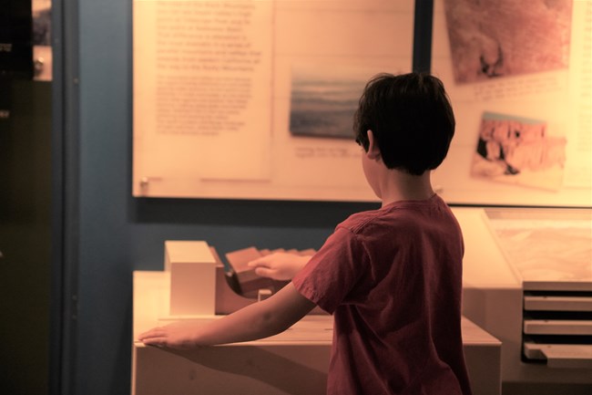 Child feeling interactive, wooden tactile geological fault demonstration in park museum