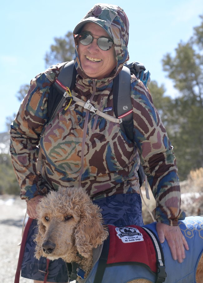 Woman in Charcoal Kilns petting service dog while on a hike.