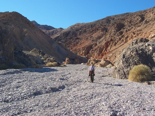 A hiker stands at the mouth of a canyon.