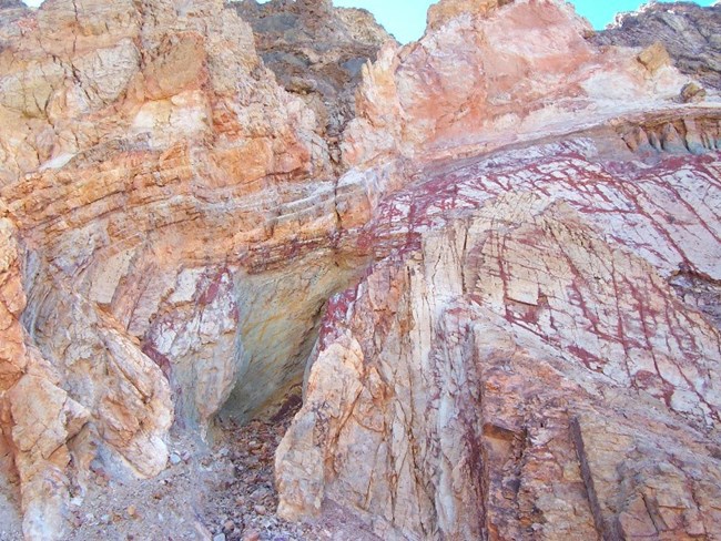 A canyon wall is riddled with colorful veins of mineral deposits.