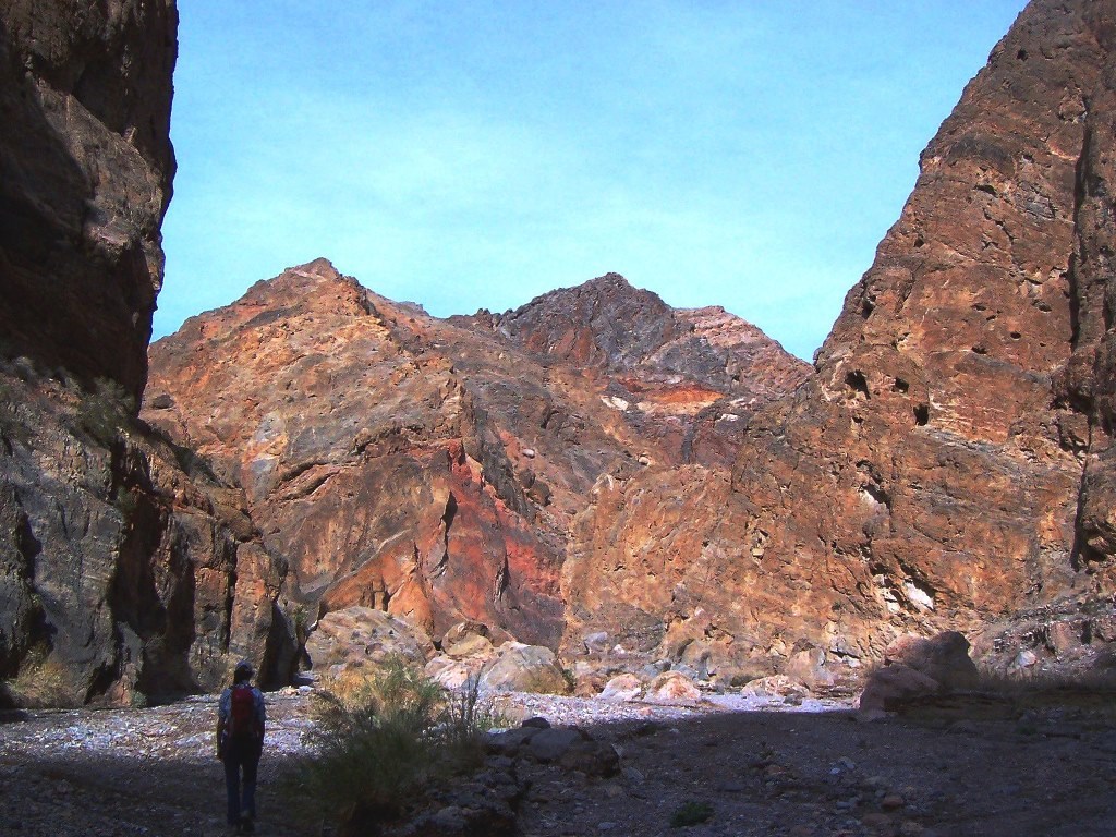 A hiker walks up canyon toward mountains