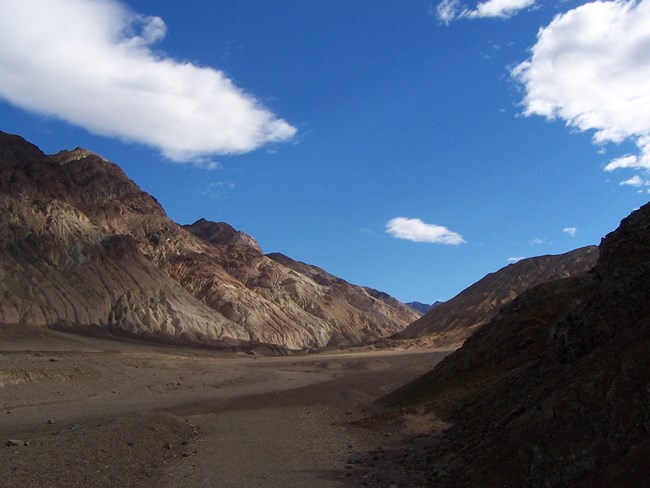 A mountain canyon beneath a cloudy blue sky.