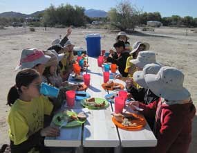 Students eat lunch on a picnic table. Students eat lunch on a picnic table.