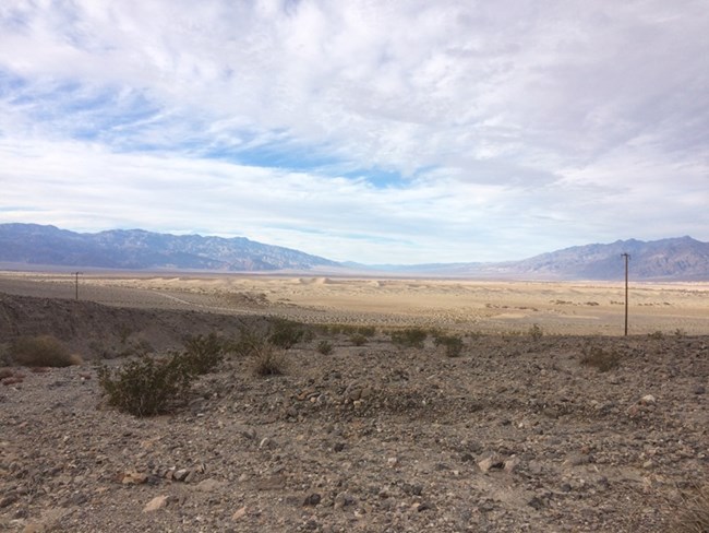 Sand dunes on the far horizon with a highway in the foreground.