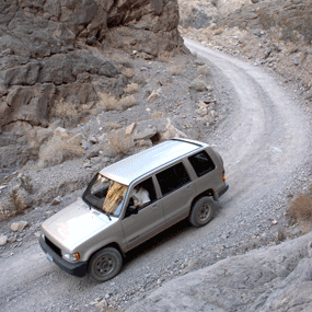 An SUV drives a backcountry road through narrow canyon.