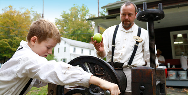 child turning the wheel of an apple press child turning the wheel of an apple press