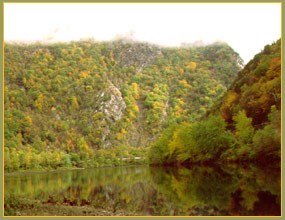 A mountain above a river, its top covered in mist