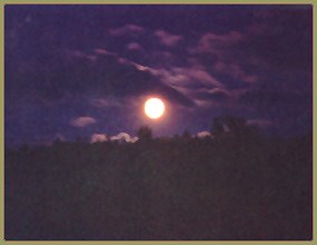 Full moon in a cloudy sky, over a ridge