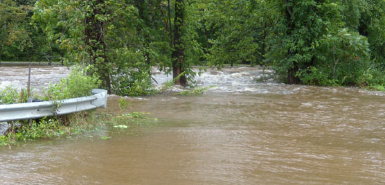 muddy creek overflowing its banks onto road