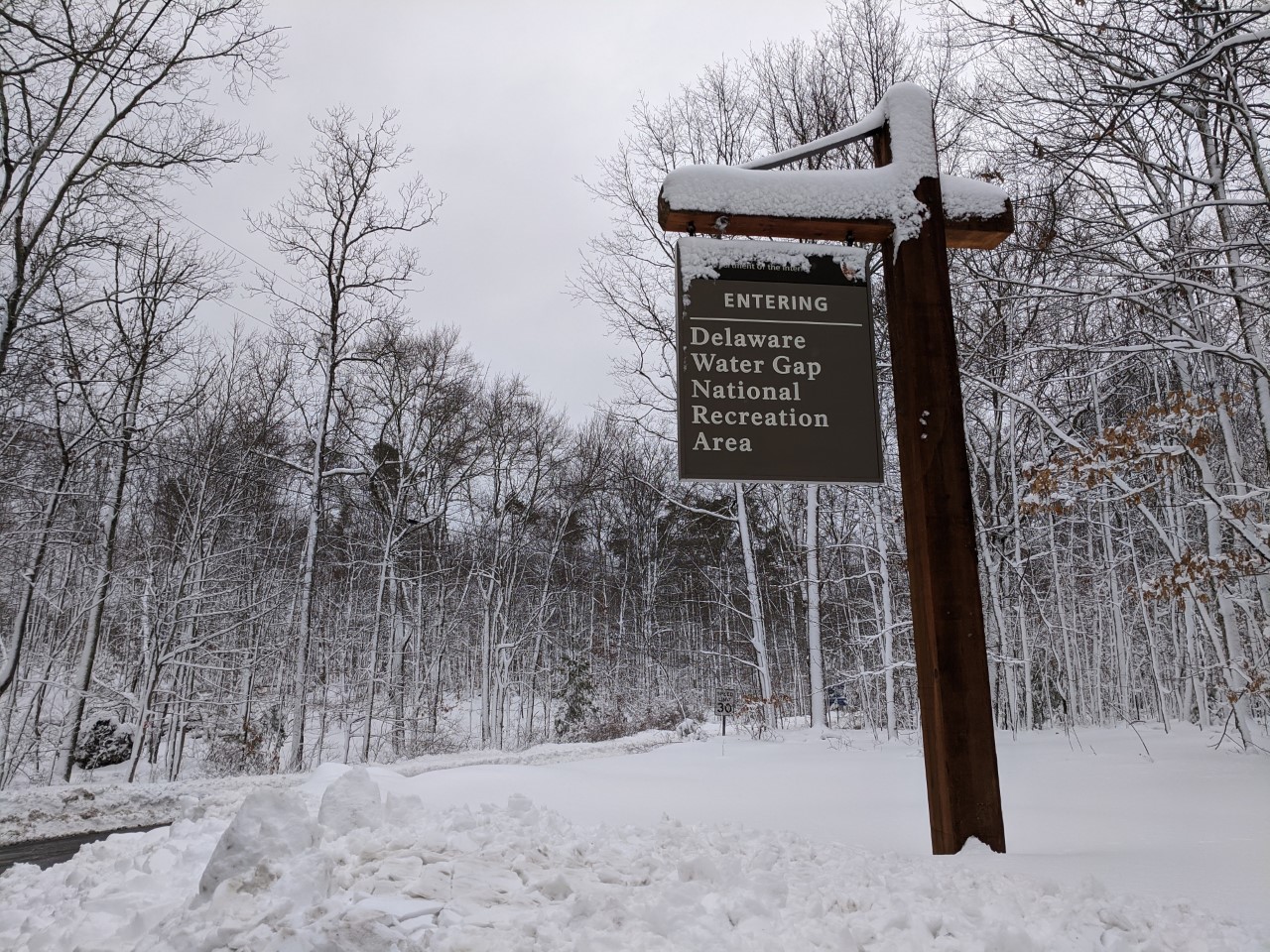 Park sign with snow in winter A snow-covered sign welcomes visitors to Delaware Water Gap National Recreation Area on a cloudy and snowy winter day.