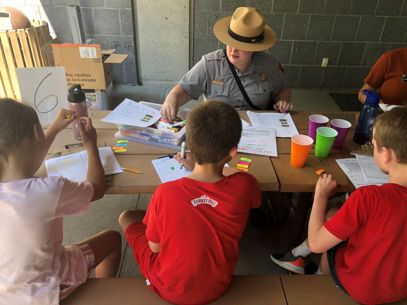 A ranger and students doing a science activity at a picnic table.