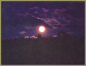 Full moon in a cloudy sky, over a ridge