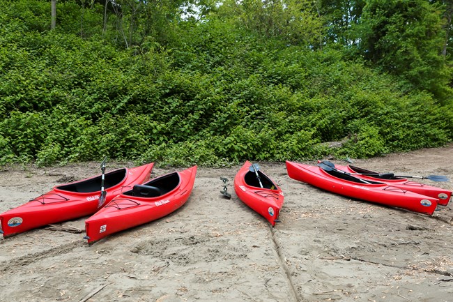 Four Kayaks from a local livery sit on the river edge at Kittatinny Point pointing like fingers stretched on a hand