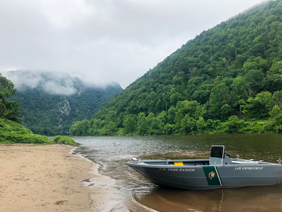 A law enforcement division boat sits at Kittatinny Point boat landing with the Delaware Water Gap shrouded in clouds behind