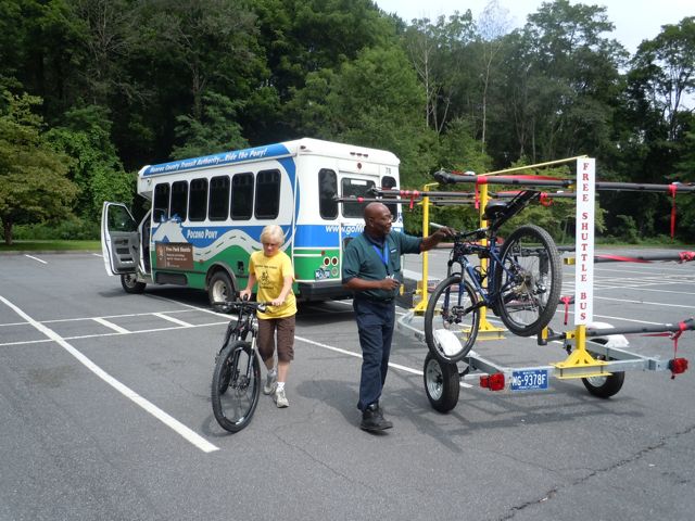 River Runner Shuttle A shuttle towing a trailer and people putting bikes on the trailer.