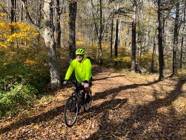 A man, wearing a helmet, bicycles on the McDade Trail.