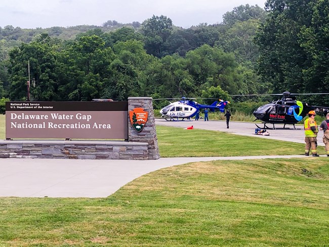 A hospital rescue helicopter sits on pavement with a sign to the left reading Delaware Water Gap National Recreation Area