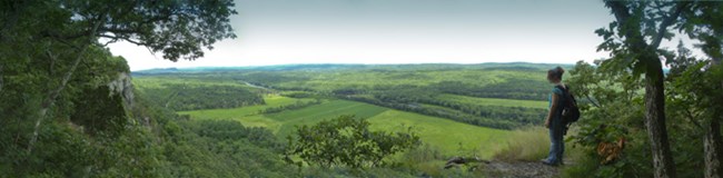 hiker at an overlook of the river valley