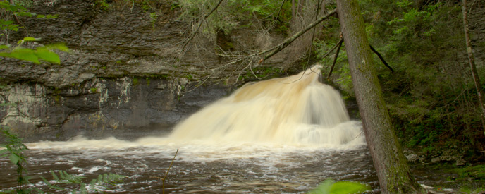 waterfall fanning over rocks into a pool of water waterfall fanning over rocks into a pool of water