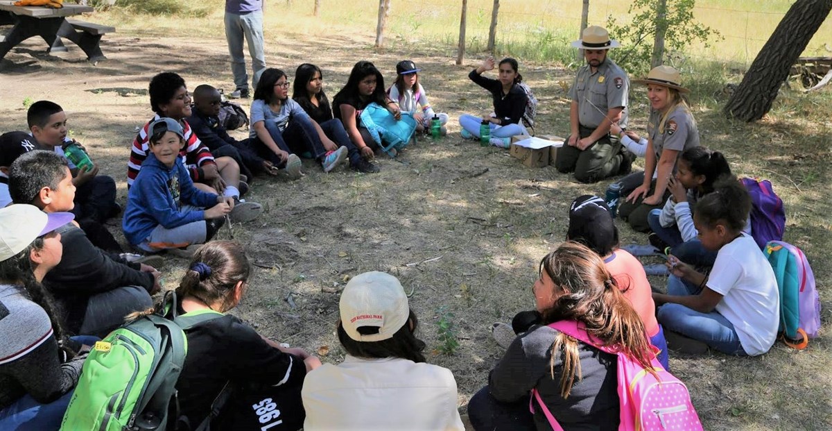 Students and Rangers sit in a circle on a field trip.