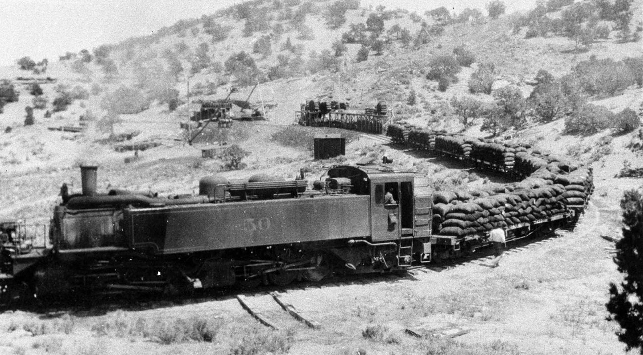 Uintah Railway hauling Gilsonite A black and white steam train curves around a bend.