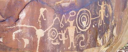 Human figure and abstract design petroglyphs carved into sandstone darkened by desert varnish. Human figure and abstract design petroglyphs carved into sandstone darkened by desert varnish.