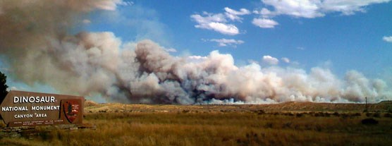 Smoke billowing high into the sky from a fire adjacent to the monument