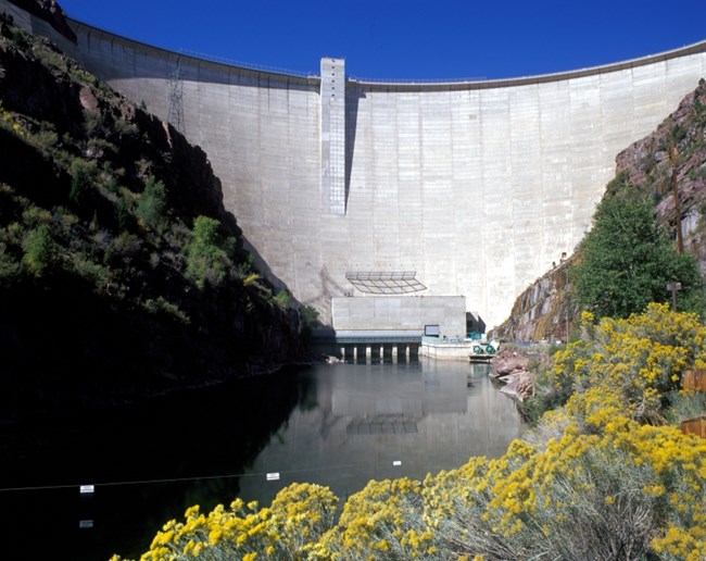 The Green River flows out from a grate in a curved white wall about 500 feet (152 meters) high.