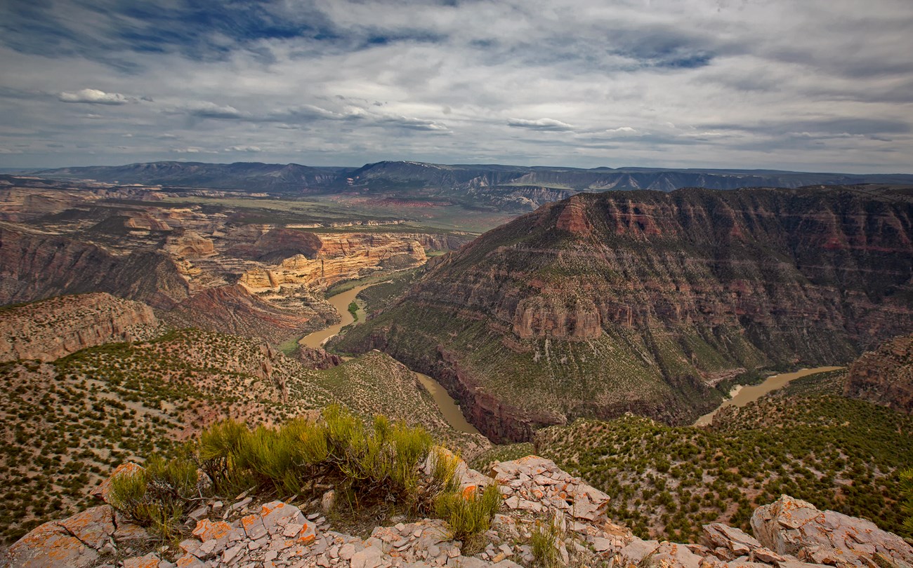 A view from high up of a river cutting through colorful, scenic rock formations.