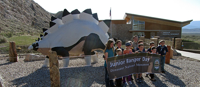 Vernal Cub Scouts hold the Junior Ranger Day Banner in front of the Quarry Visitor Center.