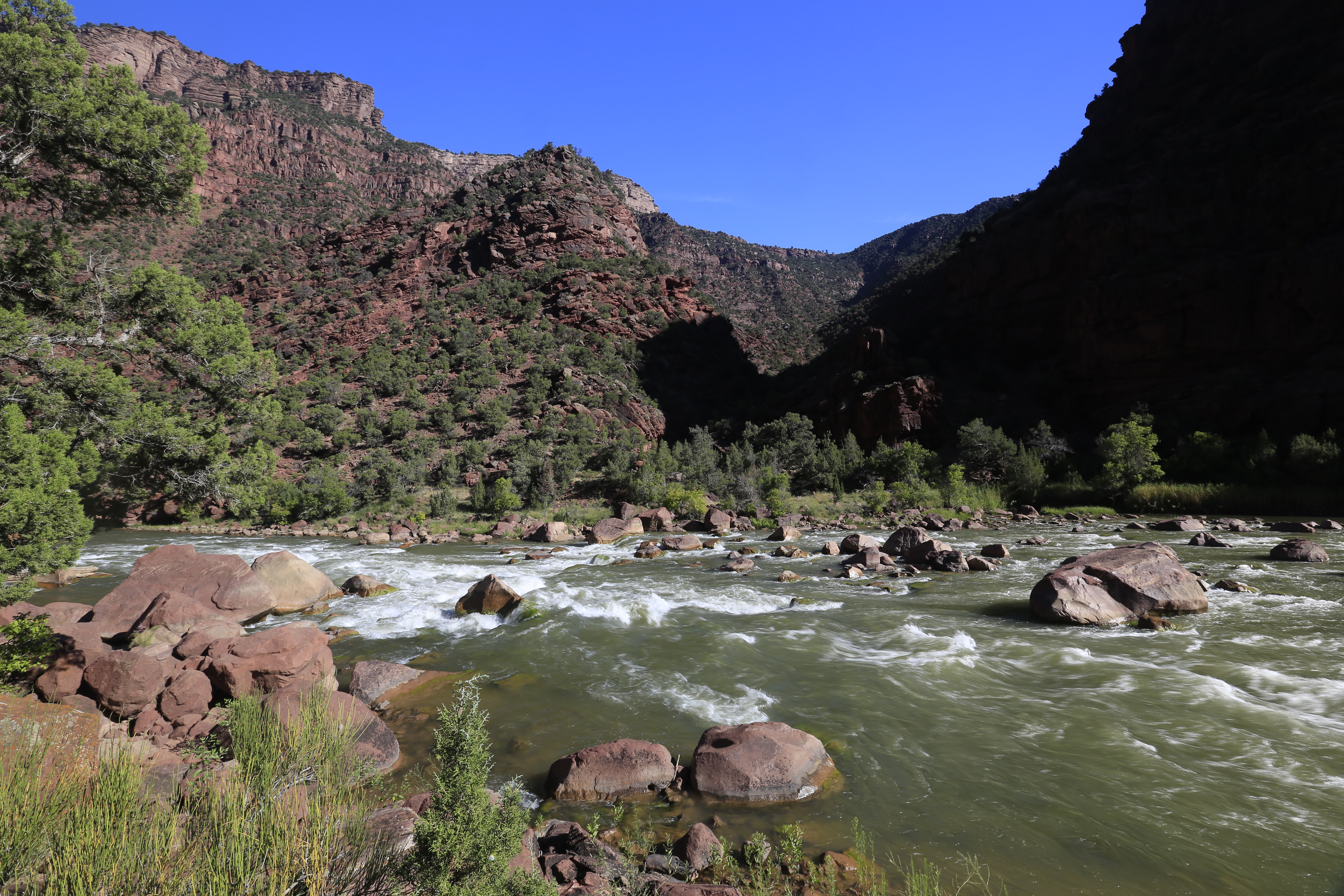 Water rushes through a boulder field of red rocks