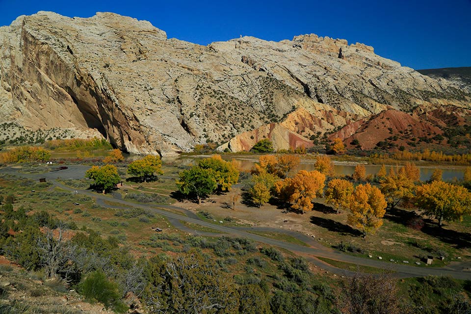 Split Mountain Area Large whitish rock mountain rising above river. Golden color trees line the rivers edge.