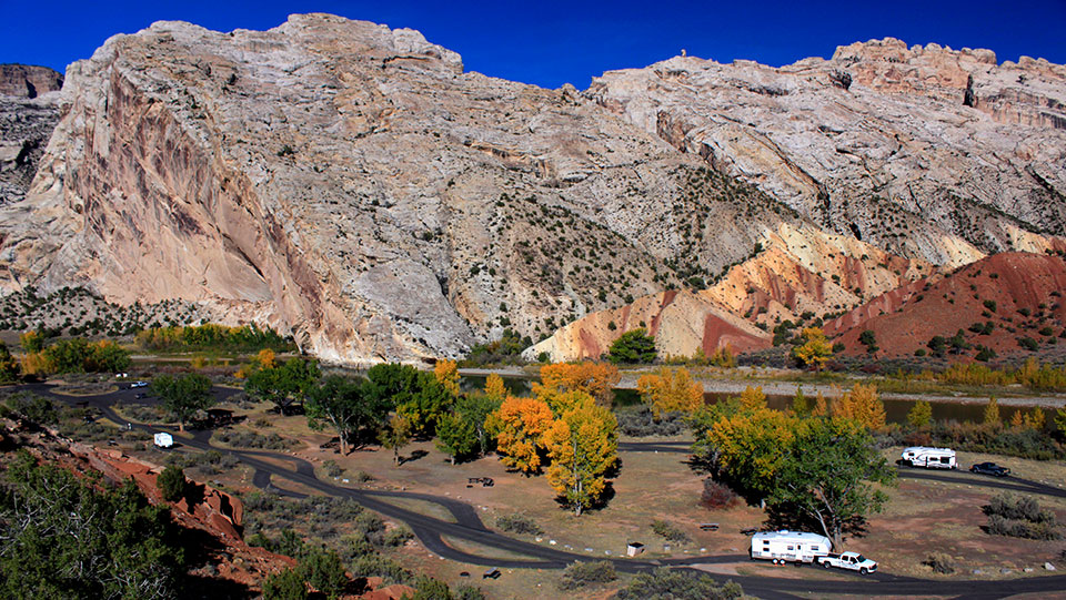 Split Mountain in Fall Rocky mountain in distance with colorful rock formation at its foot.