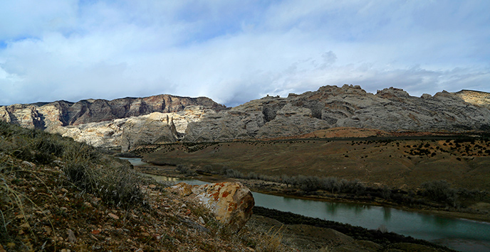 Dappled sunlight touches Split Mountain while the Green River flows along its base. Dappled sunlight touches Split Mountain while the Green River flows along its base.