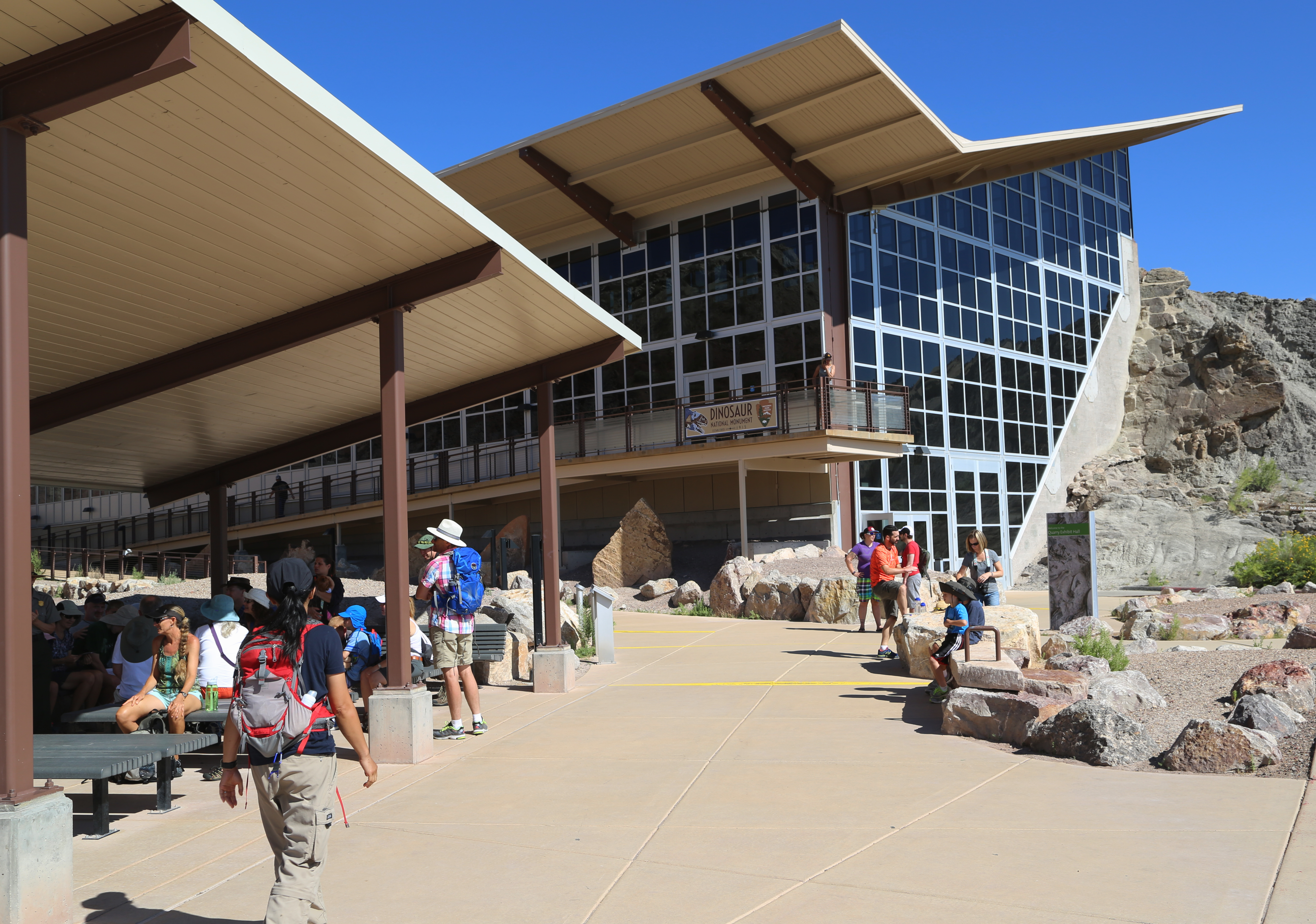 Visitors Outside the Quarry Exhibit Hall Several people walk on a sidewalk outside a building with an angled roof.