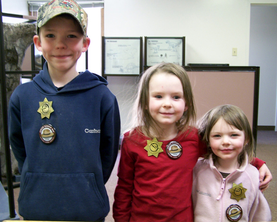 Kelton (age 7), Chloe (age 4), and Rylee (age 3) Villard of Craig, Colorado, proudly display their newly earned Junior Paleontologist badges