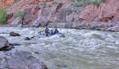 A raft with three people floats through the whitewater of Warm Springs Rapid. 