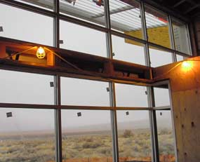 Recently installed windows, as seen from inside the building, with work lights hung above windows. 