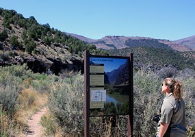 A hiker reads the trailhead sign at the start of the Gates of Lodore Trail.